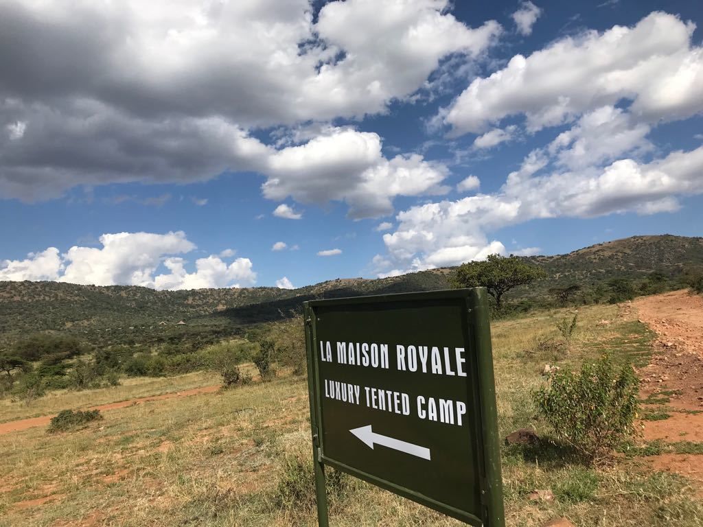 A sign for "La Maison Royale Luxury Tented Camp" with an arrow pointing to the left.