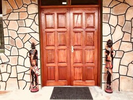 Puerta doble de madera con un muro de apariencia de piedra y dos estatuas a cada lado.