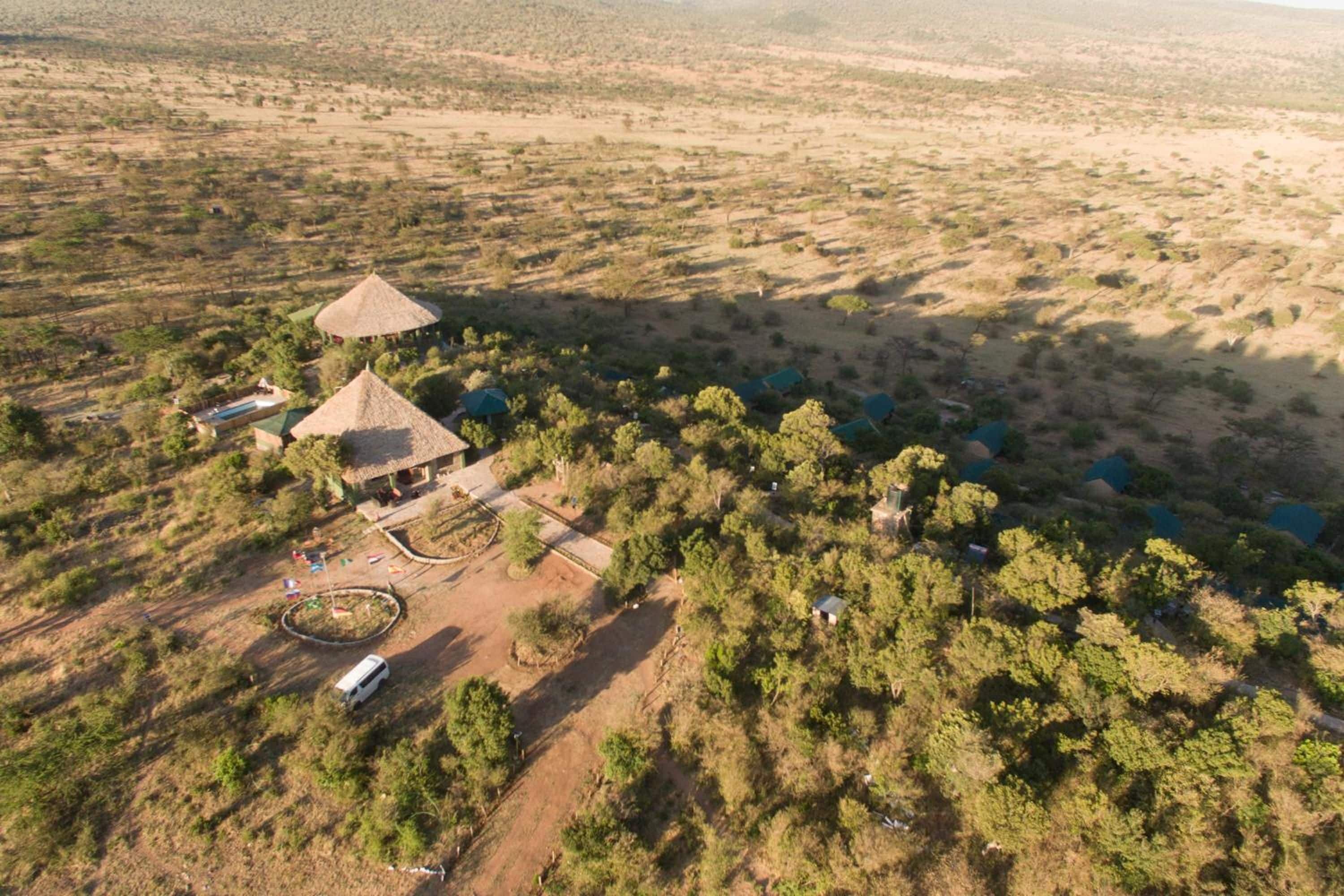 An aerial view of a rural property with a central building surrounded by trees and a few scattered structures.