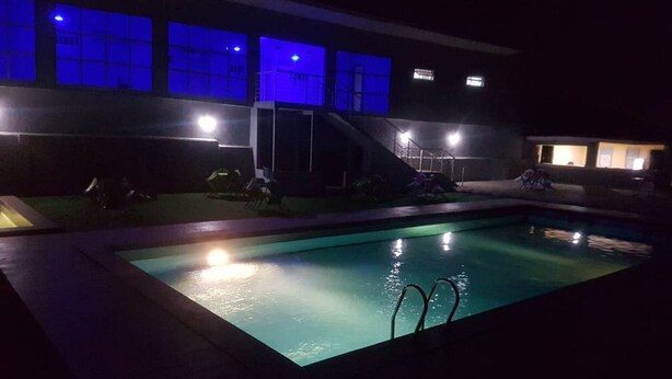Una piscina con tobogán, rodeada por un edificio con ventanas iluminadas.
