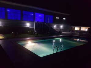 Una piscina con tobogán, rodeada por un edificio con ventanas iluminadas.