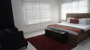 Un dormitorio con una cama, una silla y un tapete rojo.