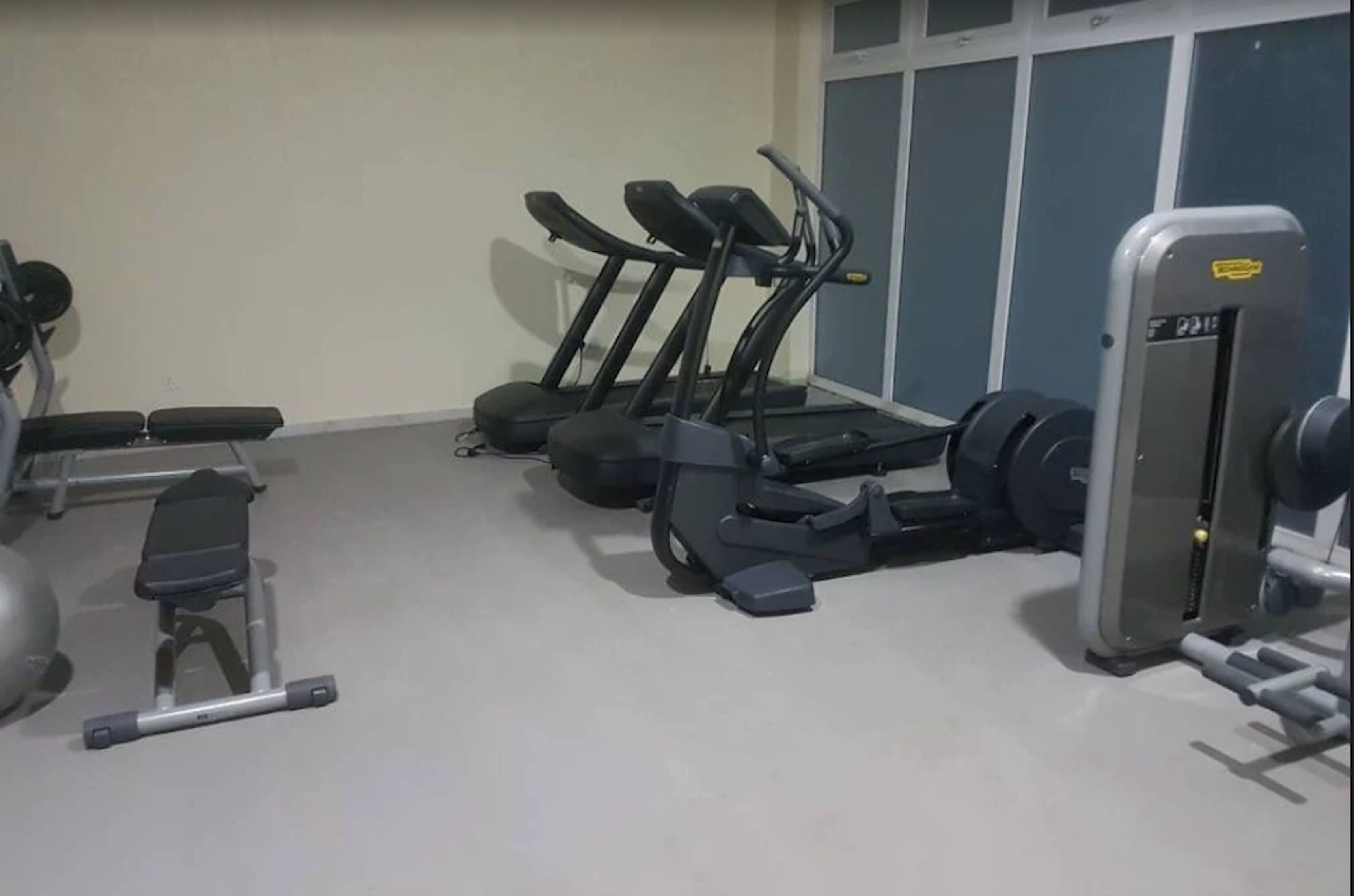 Une salle de sport équipée de tapis de course, d’appareils de musculation et d’un banc.
