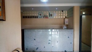 A hotel reception area with a marble counter, a seating area with a sofa, and a no-smoking sign on the wall. - Peak Court Hotels (Ibadan)