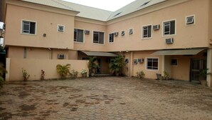 A building with a tiled courtyard, multiple windows, and potted plants. - Peak Court Hotels (Ibadan)