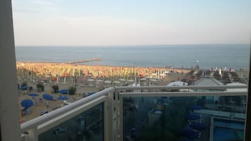 A view from a balcony overlooking a beach with umbrellas and lounge chairs.