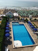 Una piscina al aire libre de temporada, sombrillas