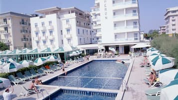 Una piscina al aire libre de temporada, sombrillas