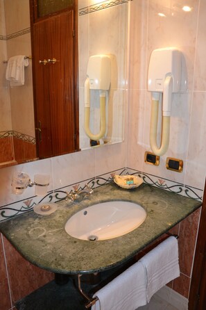 A bathroom with a sink, mirror, towel rack, and a hairdryer mounted on the wall. - Park Hotel Ravenna (Ravenna)