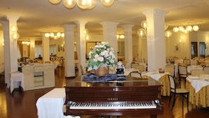 A grand dining hall with a piano, chandeliers, and white columns. - Park Hotel Ravenna (Ravenna)