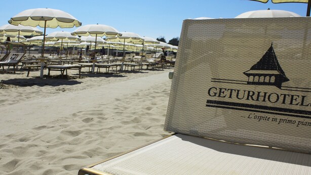 A beach with sun loungers and umbrellas, and a sign for Geturhotel. - Park Hotel Ravenna (Ravenna)