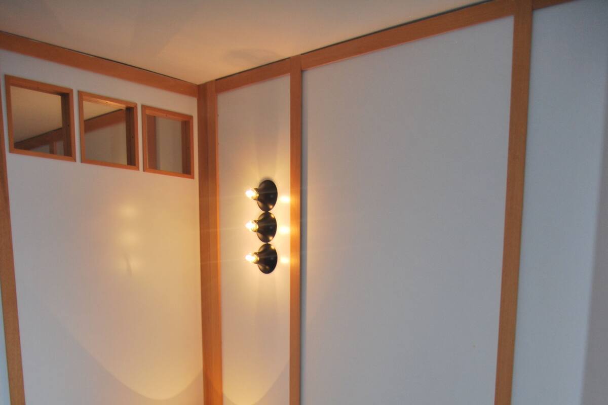 A bedroom with a bed, a bedside lamp, and a wall-mounted light fixture.