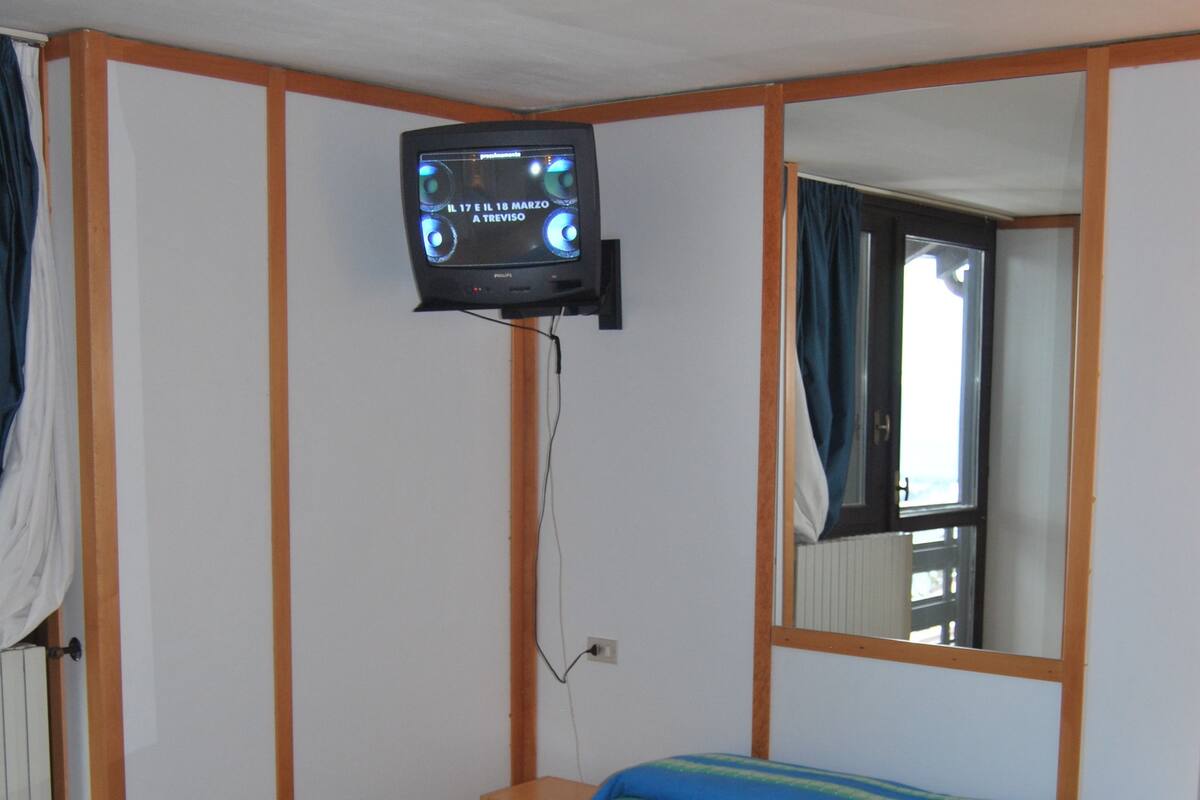 A bedroom with a bed, a television mounted on the wall, and a mirror.
