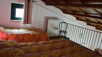 Una camera da letto con due letti, una finestra con tende, un termosifone e una sedia.