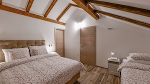 Un dormitorio con una cama grande, un armario, una mesita de noche y un techo con vigas de madera a la vista.
