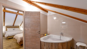 Un dormitorio con una cama grande, techo de madera y un baño con bañera.
