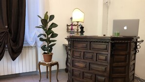 A room with a wooden cabinet, a potted plant, a lamp, and a laptop on a small stool. - Relais Puccini (Lucca)