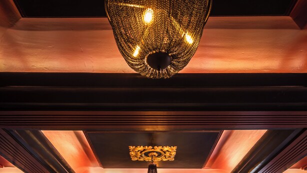 Eine Bar mit einer zentralen Theke, mehreren Flaschenregalen und vier Barhocker.