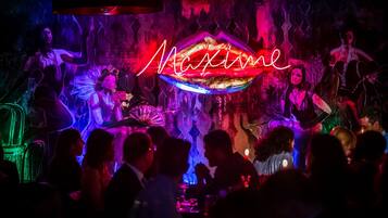 Un bar bondé, avec des enseignes au néon et un mur orné de motifs.