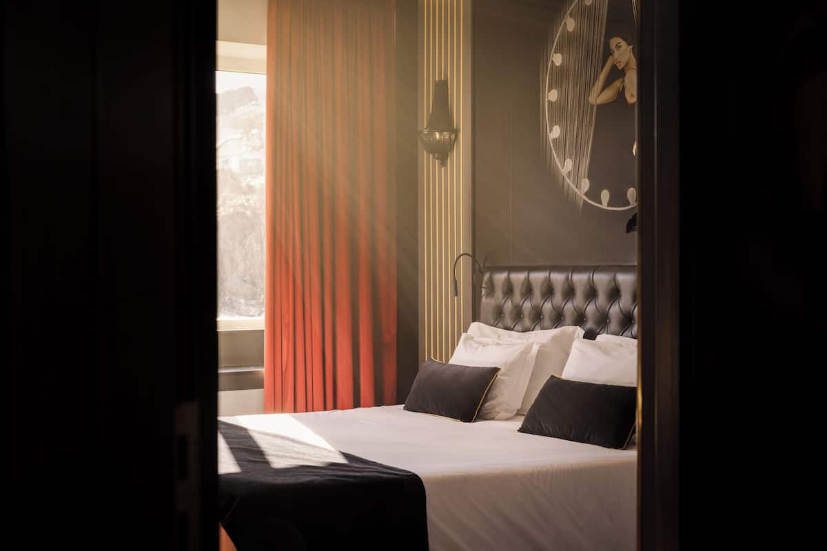 A bedroom with a bed, curtains, a wall clock, and a window.