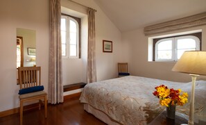 A bedroom with a bed, a chair, a desk, a lamp, and a window. - Casa do Feitor (Funchal)
