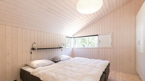 Un dormitorio con una cama grande, paredes de madera, una ventana y una lámpara en el techo.