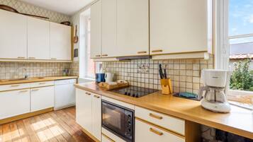 Een moderne keuken met witte kasten, een houten aanrecht, een inbouwoven en een koffiezetapparaat.