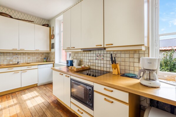 Eine moderne Küche mit weißen Schränken, einer Holzarbeitsplatte, einem eingebauten Backofen und einer Kaffeemaschine.