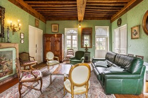 Una habitación con un sofá verde, un armario de madera y una lámpara de araña.