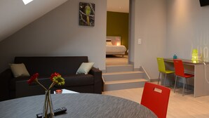 Um apartamento moderno com quarto em estilo loft, área de jantar e sala de estar.