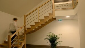 Uma escadaria de madeira com uma placa acima que diz "Résidence Appartement en Ville".