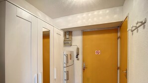 Un pasillo con una puerta amarilla cerrada, una puerta blanca y un armario blanco.