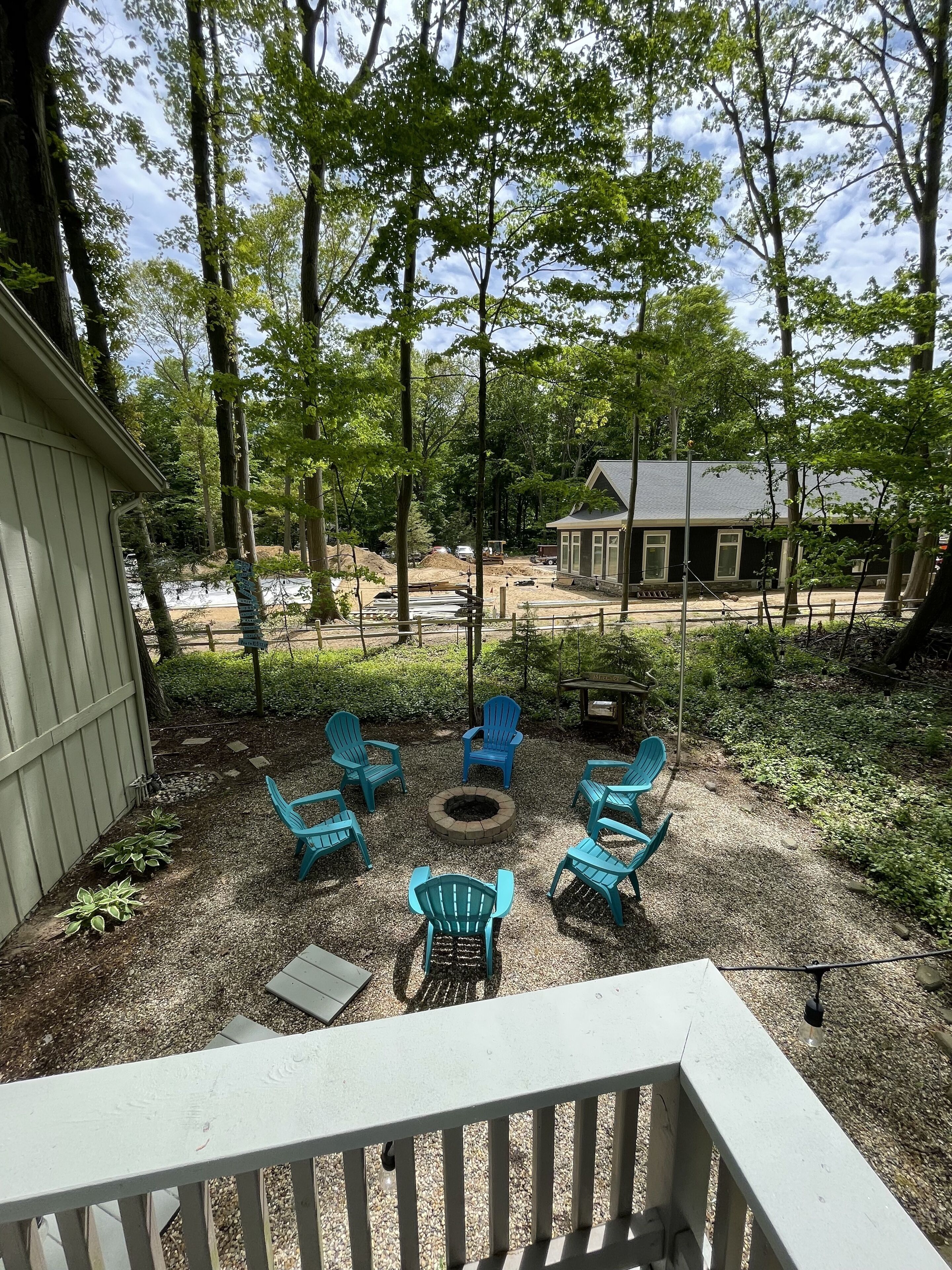 A patio with outdoor seating and a fire pit, surrounded by trees and a construction site in the background.