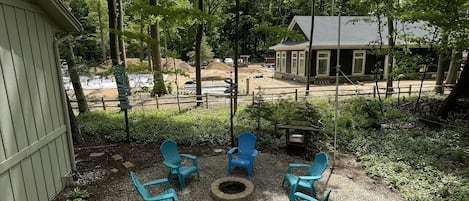 A patio with outdoor seating and a fire pit, surrounded by trees and a construction site in the background.