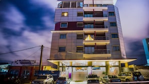 A multi-story hotel with a prominent 'HOME' sign at the entrance, featuring a modern architectural design with balconies and large windows. - Home Residence Hotel (Cotonou)