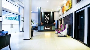 A modern hotel lobby with a reception desk, seating area, and large windows. - Home Residence Hotel (Cotonou)