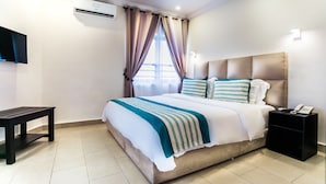 A modern hotel room with a large bed, a bedside table, a nightstand, and a flat-screen TV mounted on the wall. - Home Residence Hotel (Cotonou)