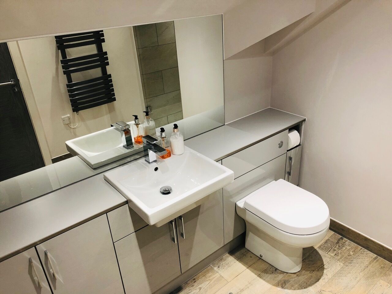A modern bathroom with a white sink, a toilet, and a mirror.