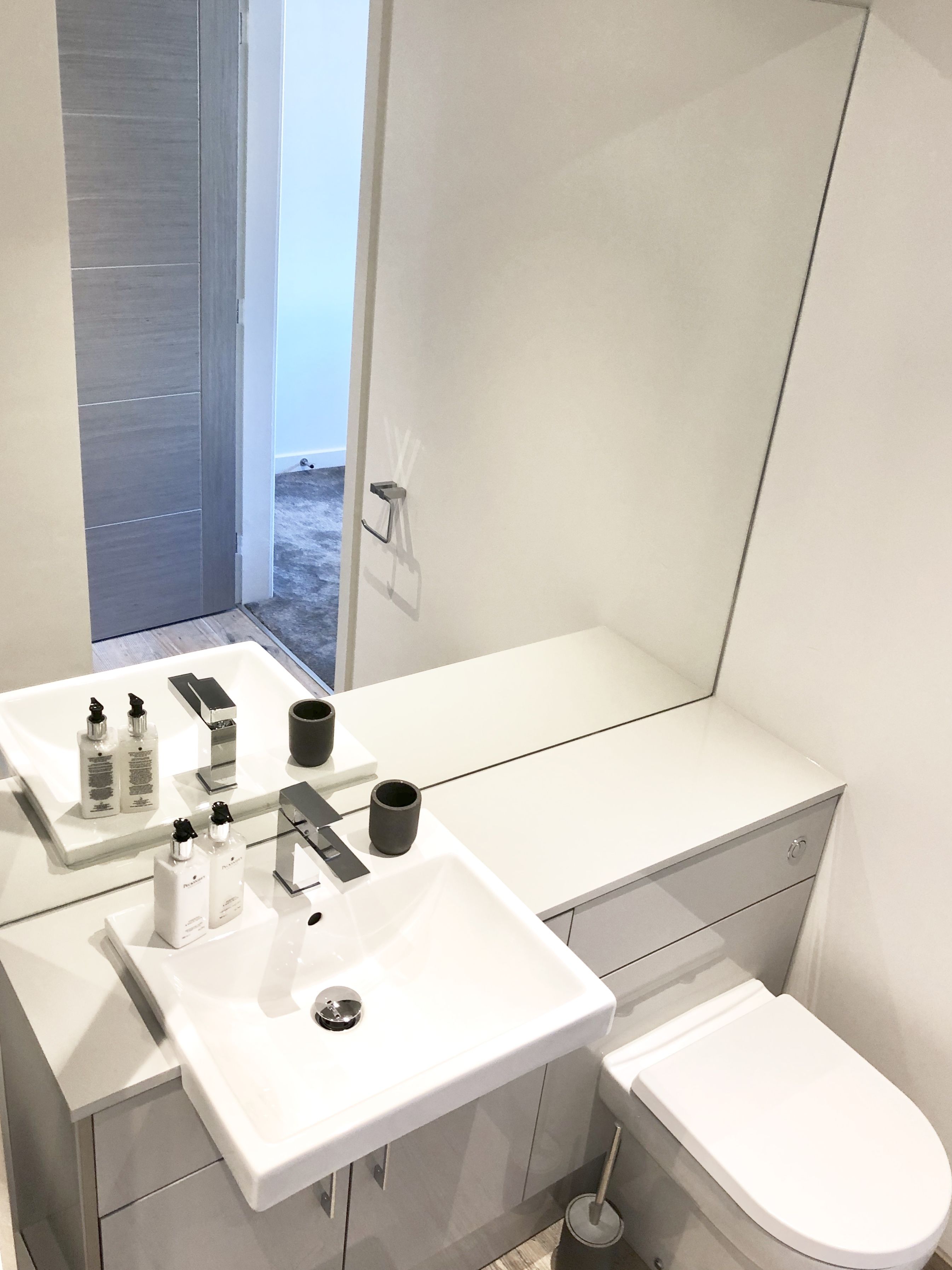 A modern bathroom with a white sink, a toilet, and a shower area.