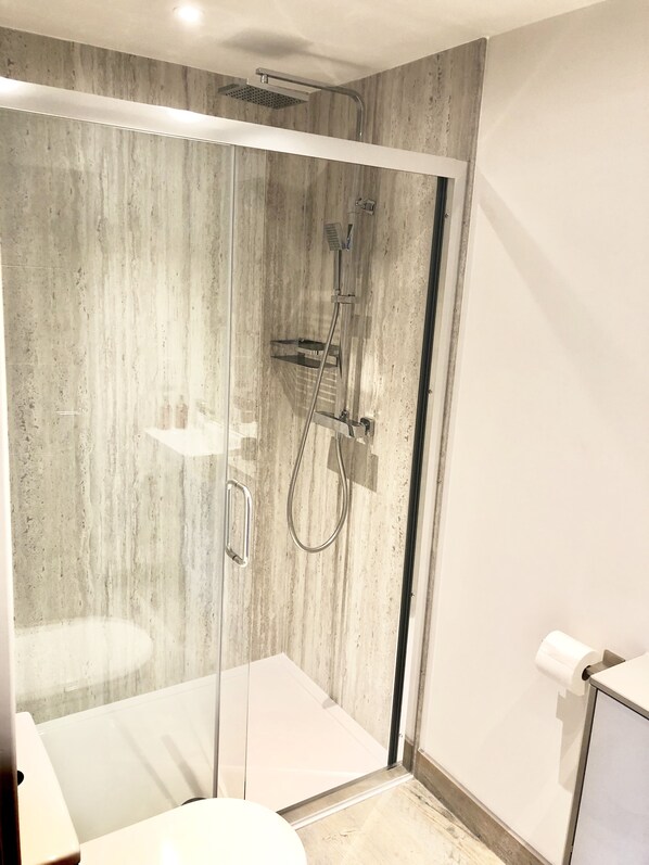 A modern bathroom with a glass-enclosed shower, a toilet, and a sink.