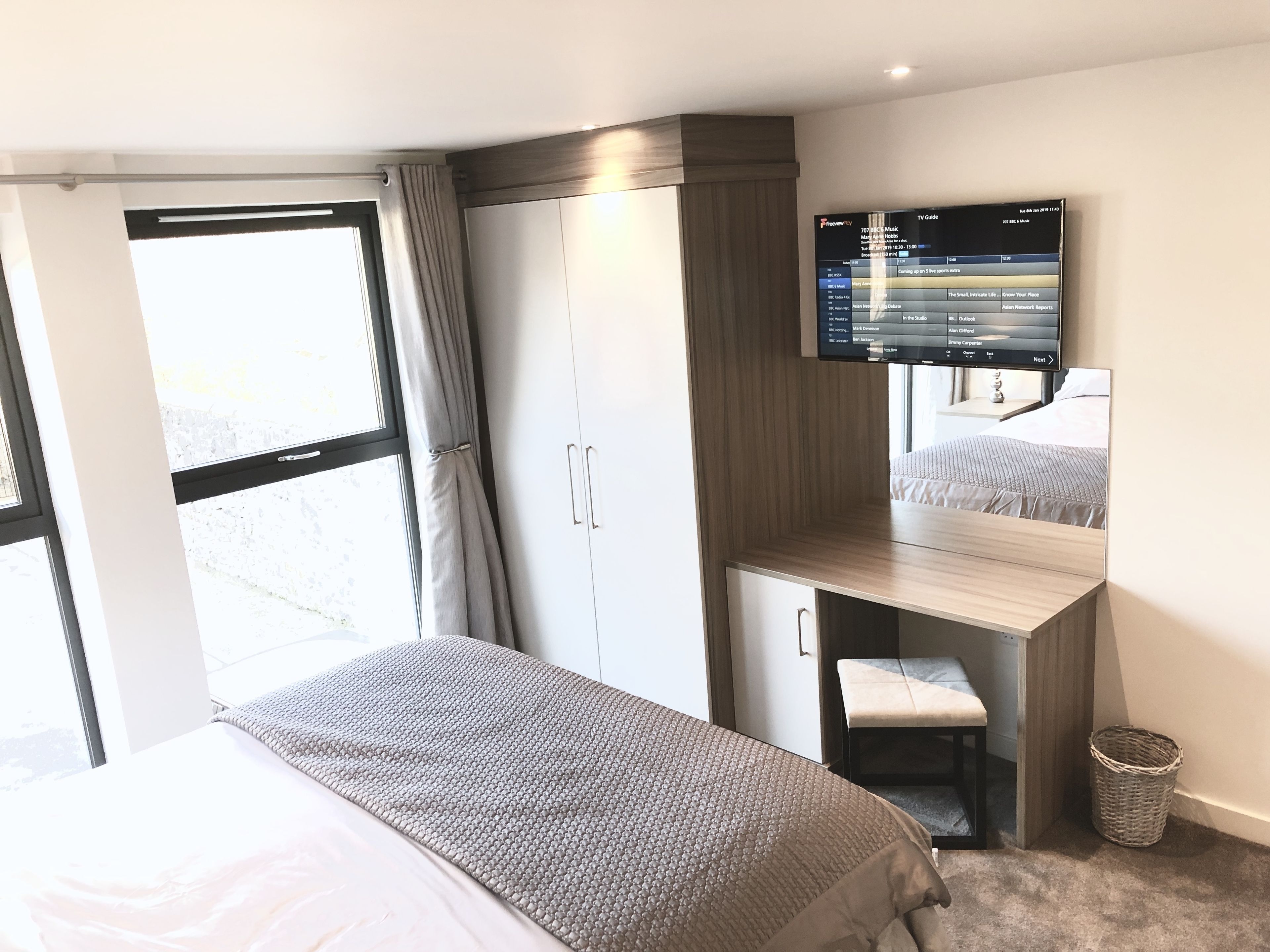 A hotel room with a bed, a desk, a TV, and a wardrobe.