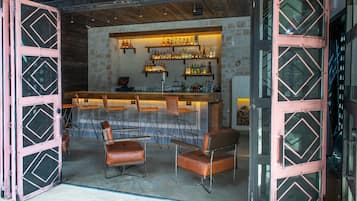 Un área de bar con pared de piedra, techo de madera y taburetes.