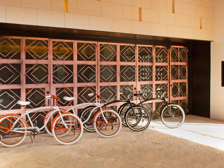 A row of bicycles parked in front of a garage with a decorative metal gate.