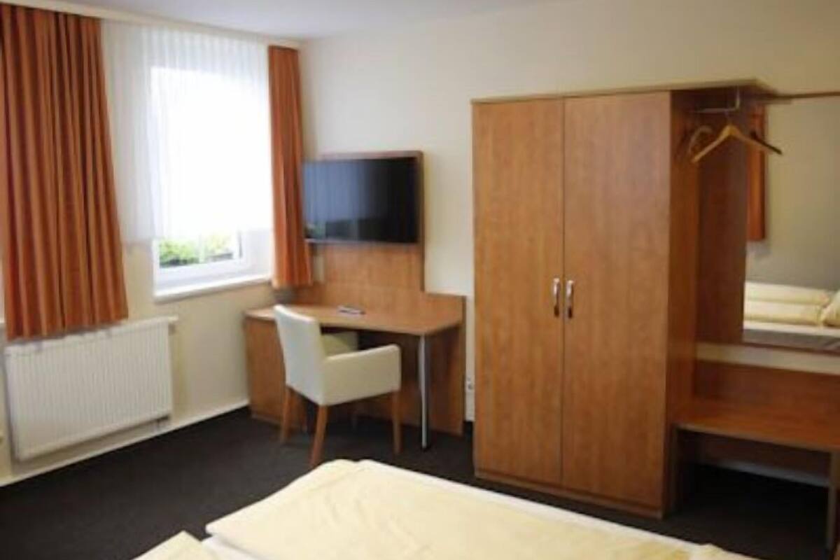 Une chambre d’hôtel équipée d’un lit, d’un bureau, d’une chaise, d’une armoire et d’un téléviseur.