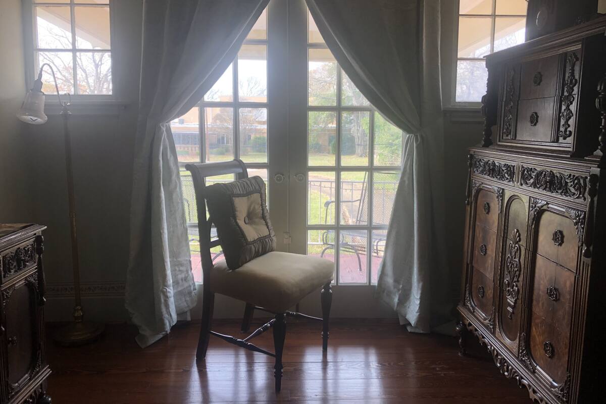 A room with a wooden chair, a cabinet, and a window with curtains.