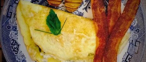 Een bord met een omelet, spek en gebakken aardappelen.