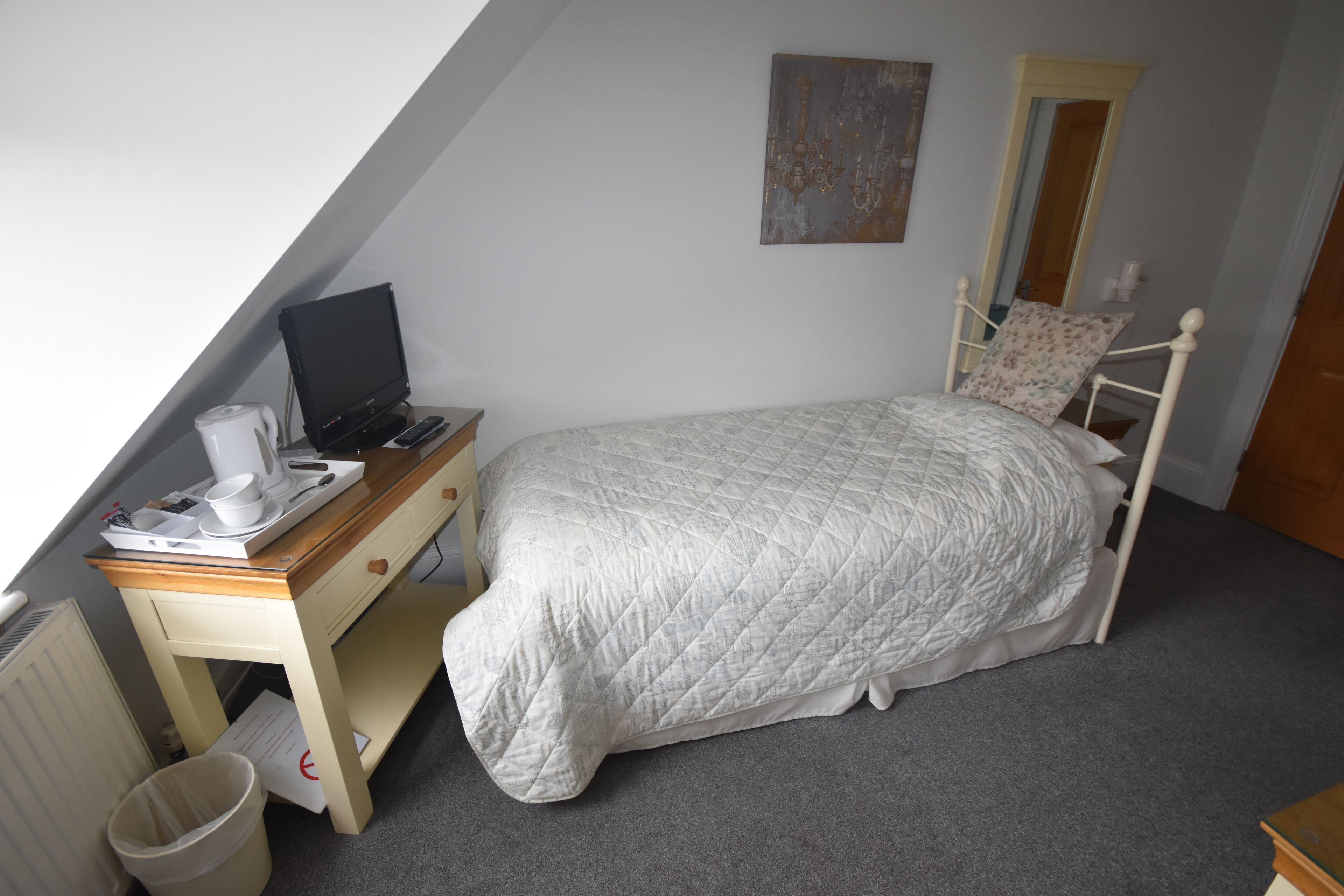 Une chambre à coucher avec un lit, un bureau avec un ordinateur et un radiateur.
