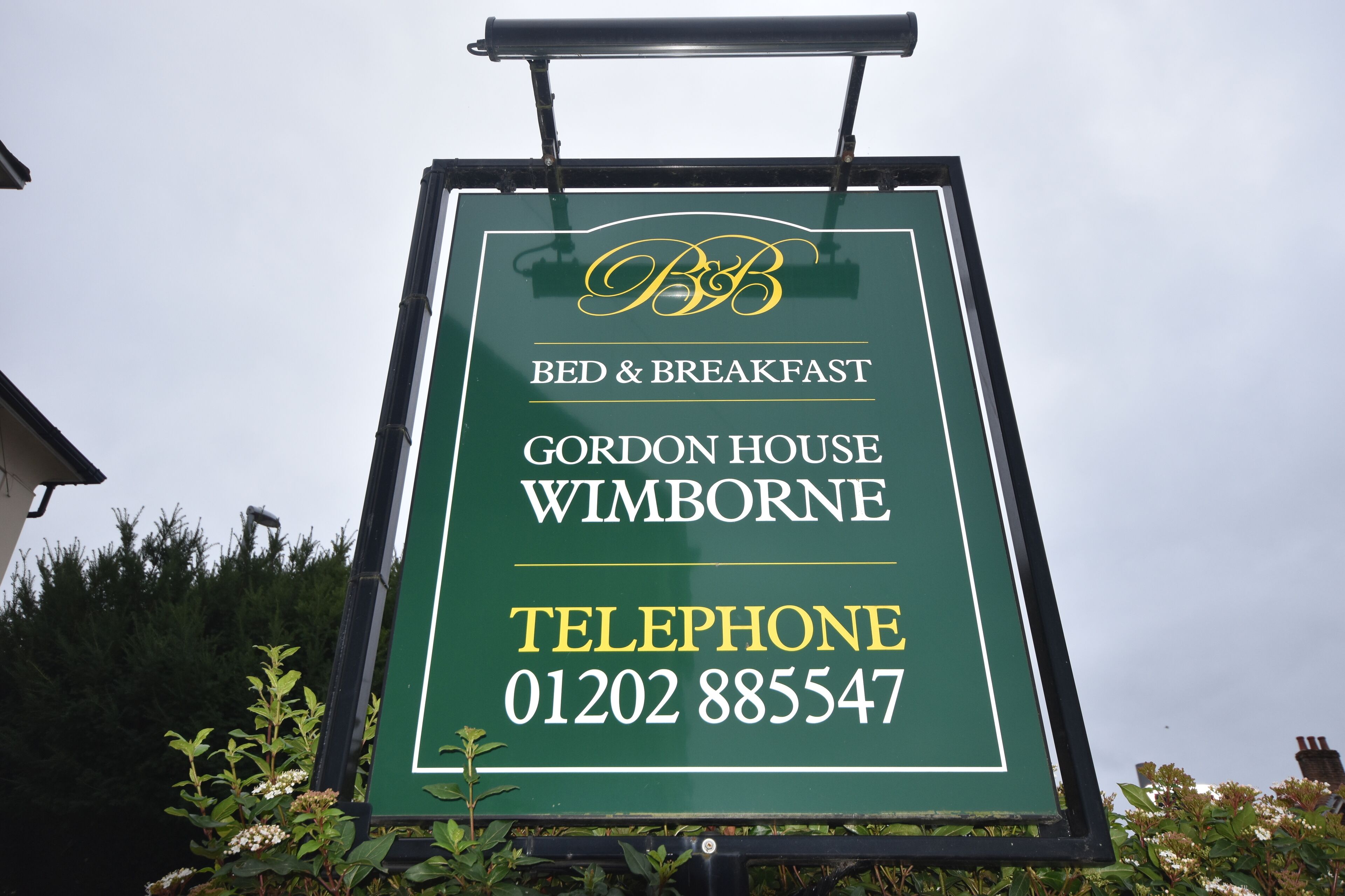 A sign for Gordon House Bed & Breakfast in Wimborne, including a telephone number.