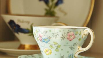 Une tasse à thé et sa soucoupe, toutes deux ornées d’un motif floral, sont posées sur une table.