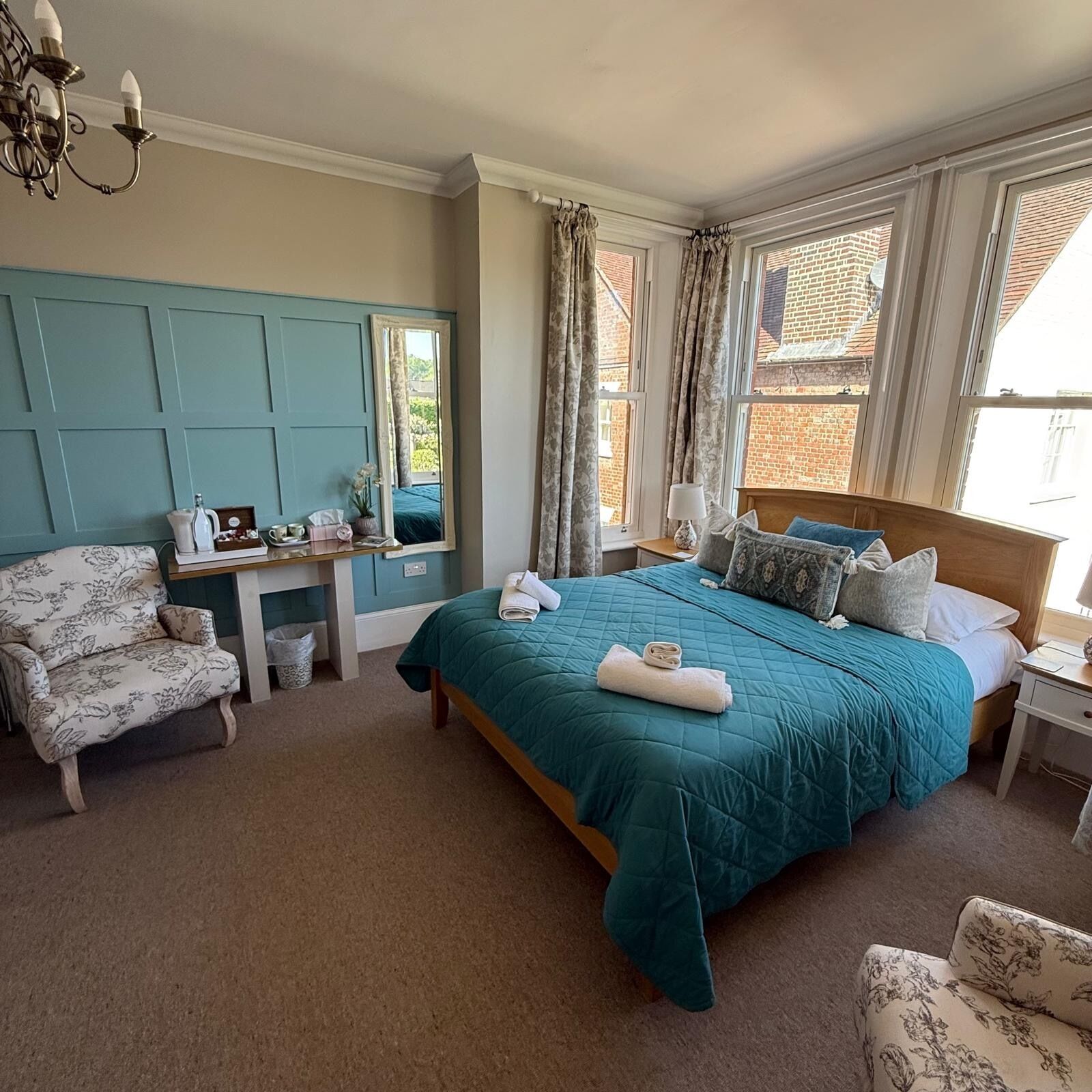 A bedroom with a bed, a desk, a chair, and a window with curtains.